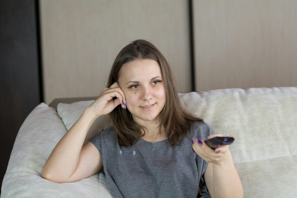Woman turning up the TV volume, early sign of age-related hearing changes, natural hearing support supplement concept