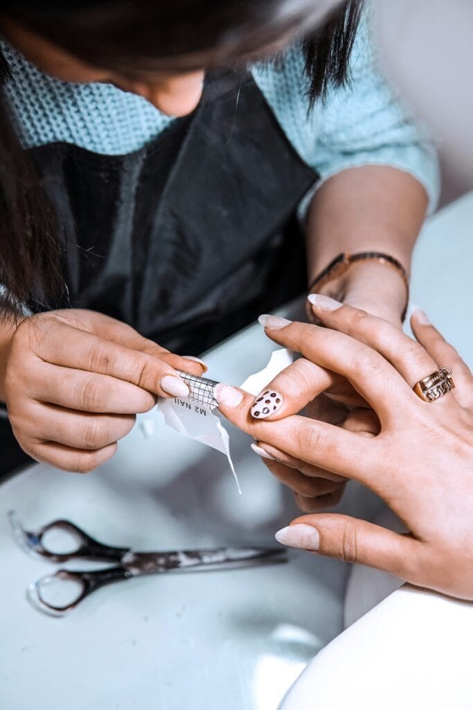 Nails peeling — woman examining her nails and hands, early sign of collagen decline